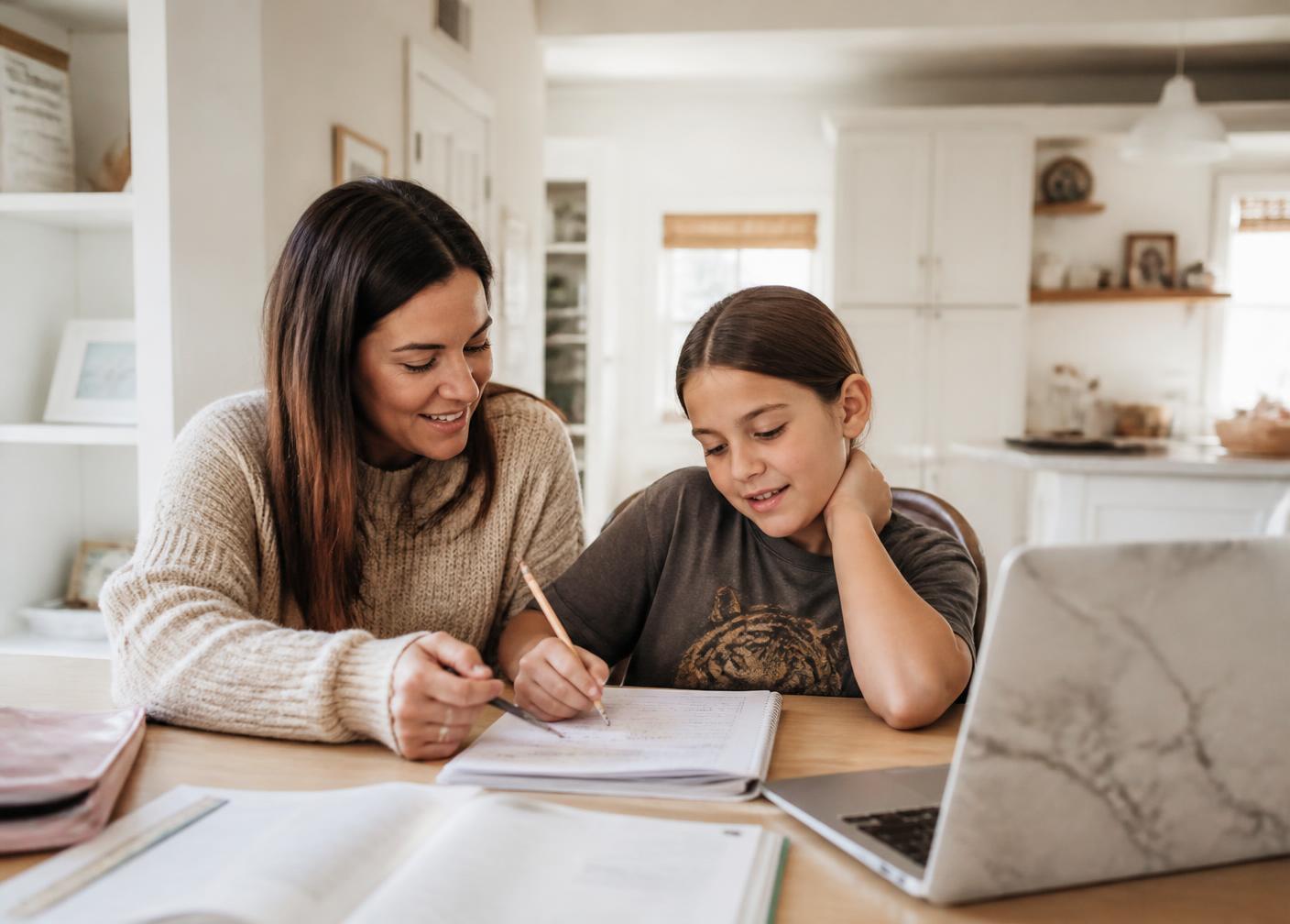 Madre acompañando a su hija durante una jornada de homeschooling en casa